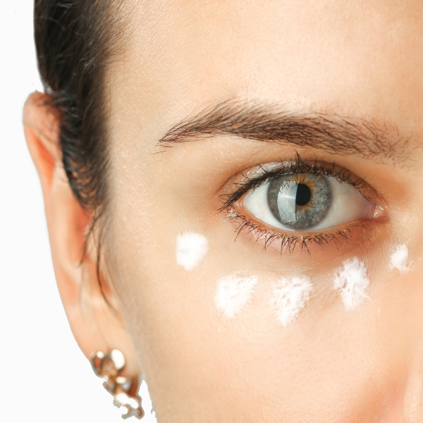 Close-up of a woman's eye with light makeup and earrings on a white background