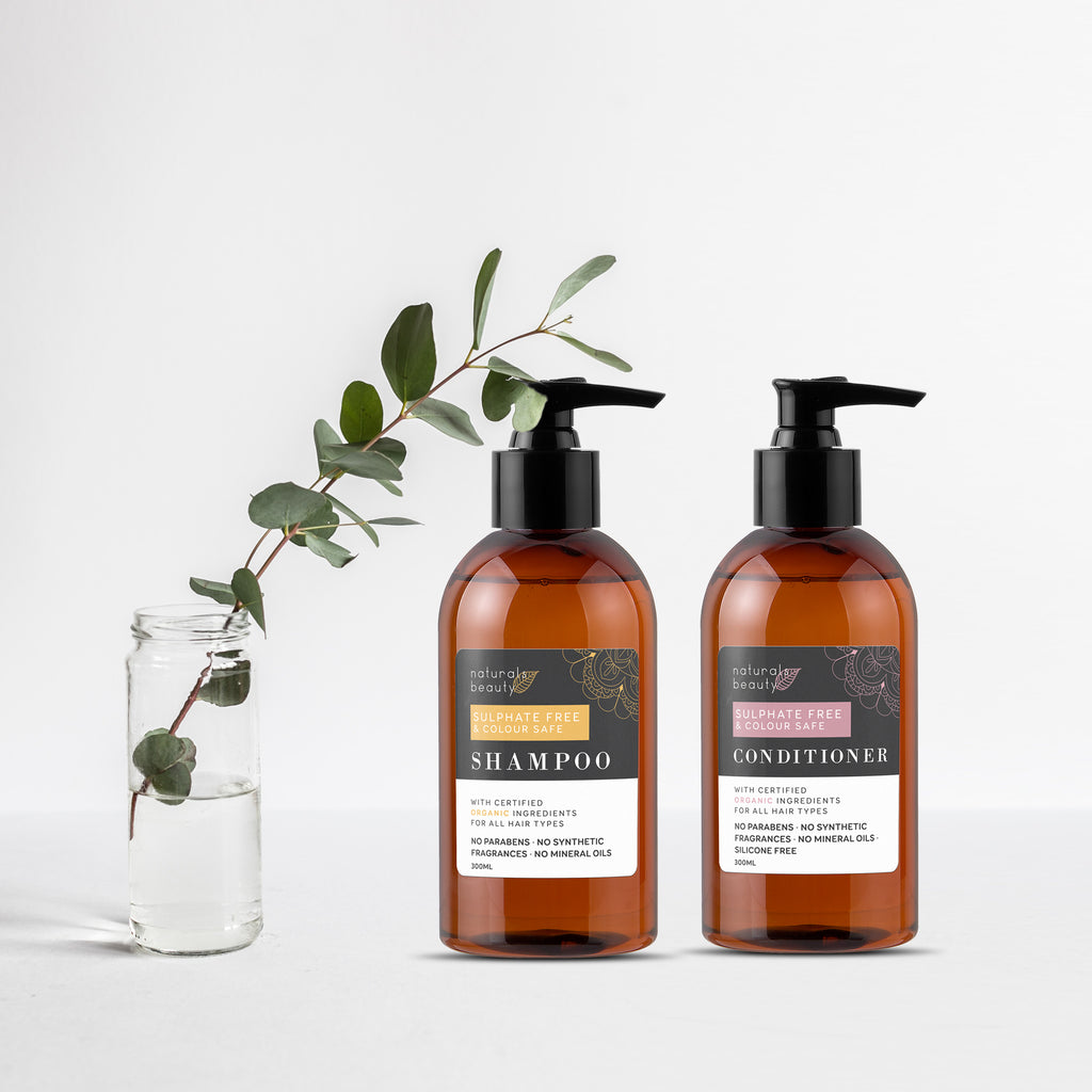 Two bottles of shampoo and conditioner with a plant on a white background