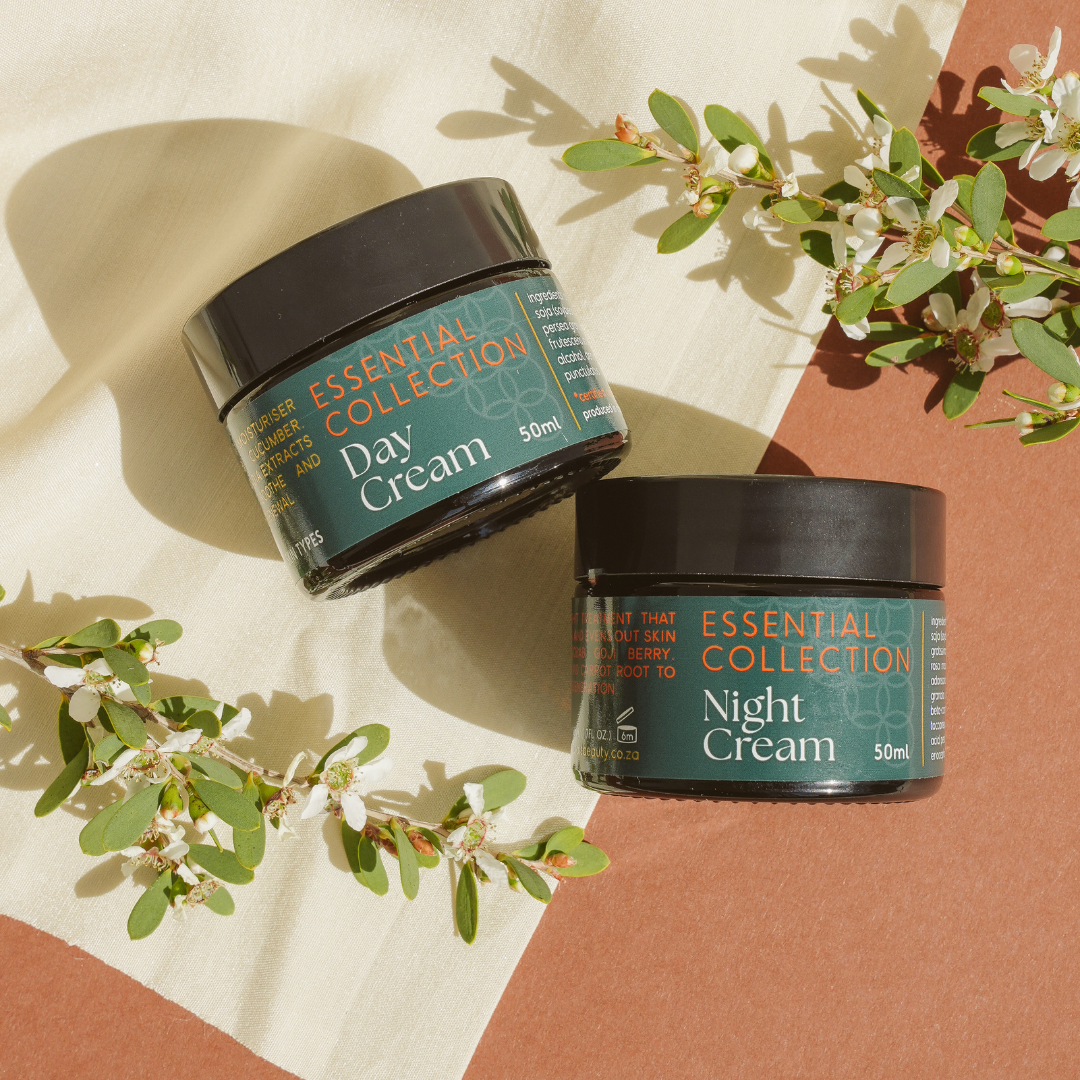 Two jars of Essential Collection Day Cream and Night Cream on a patterned background with greenery.
