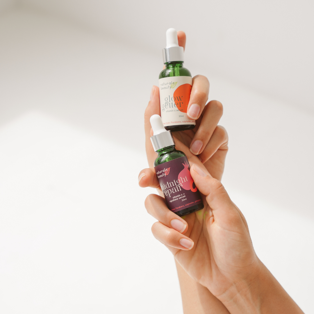 Glow Getter and Midnight Repair face serums held by a hand against a plain background