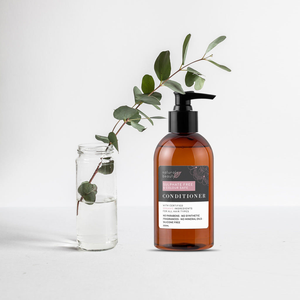 Bottle of conditioner with a label and a branch of eucalyptus on a light background