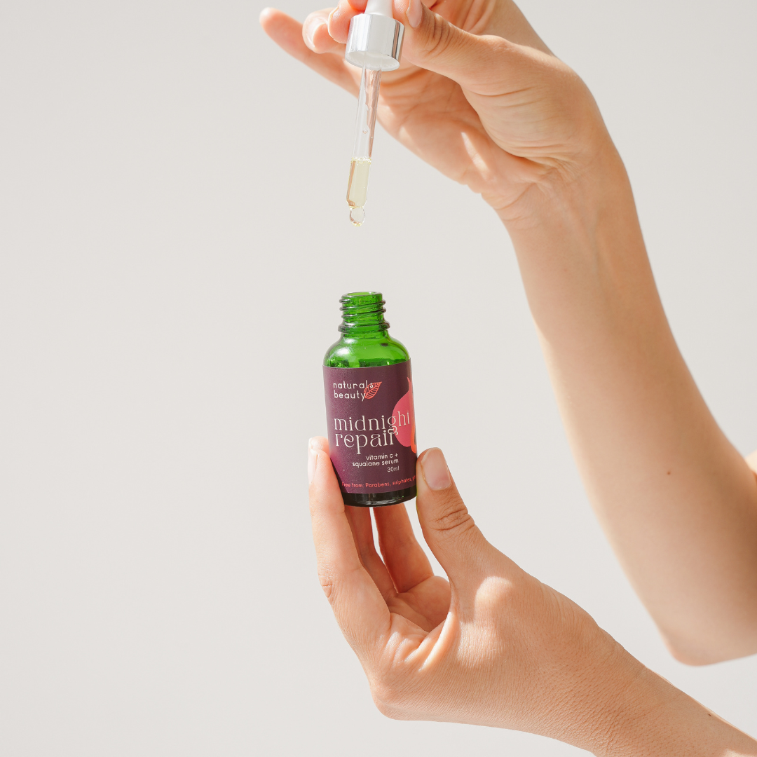 Hand holding a bottle of 'Midnight Repair' serum with a dropper.
