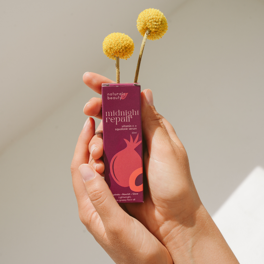Hand holding a purple skincare product labeled 'midnight repair' with yellow flowers on a neutral background